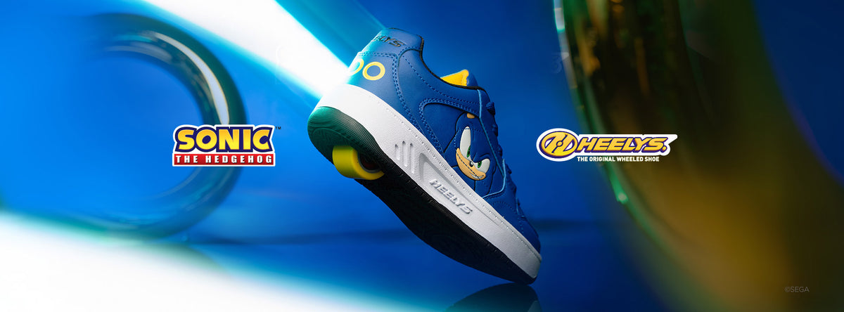 A blue and white Sonic the Hedgehog Heelys shoe with yellow accents, shown floating against a blue background with Sonic the Hedgehog and Heelys logos.