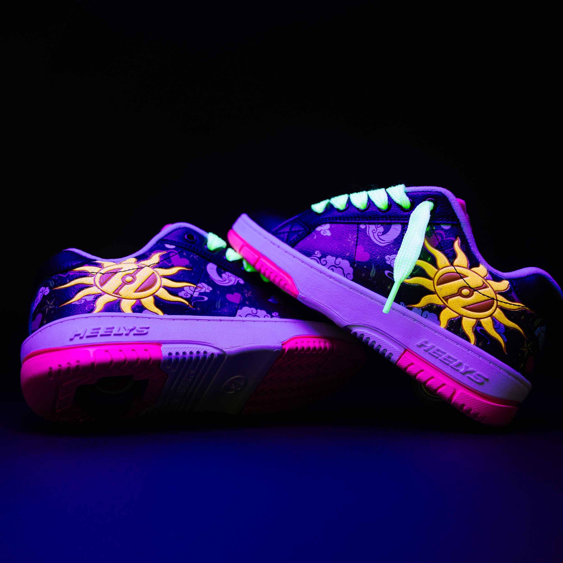 Glowing purple Heelys roller shoes with sun design on a black background