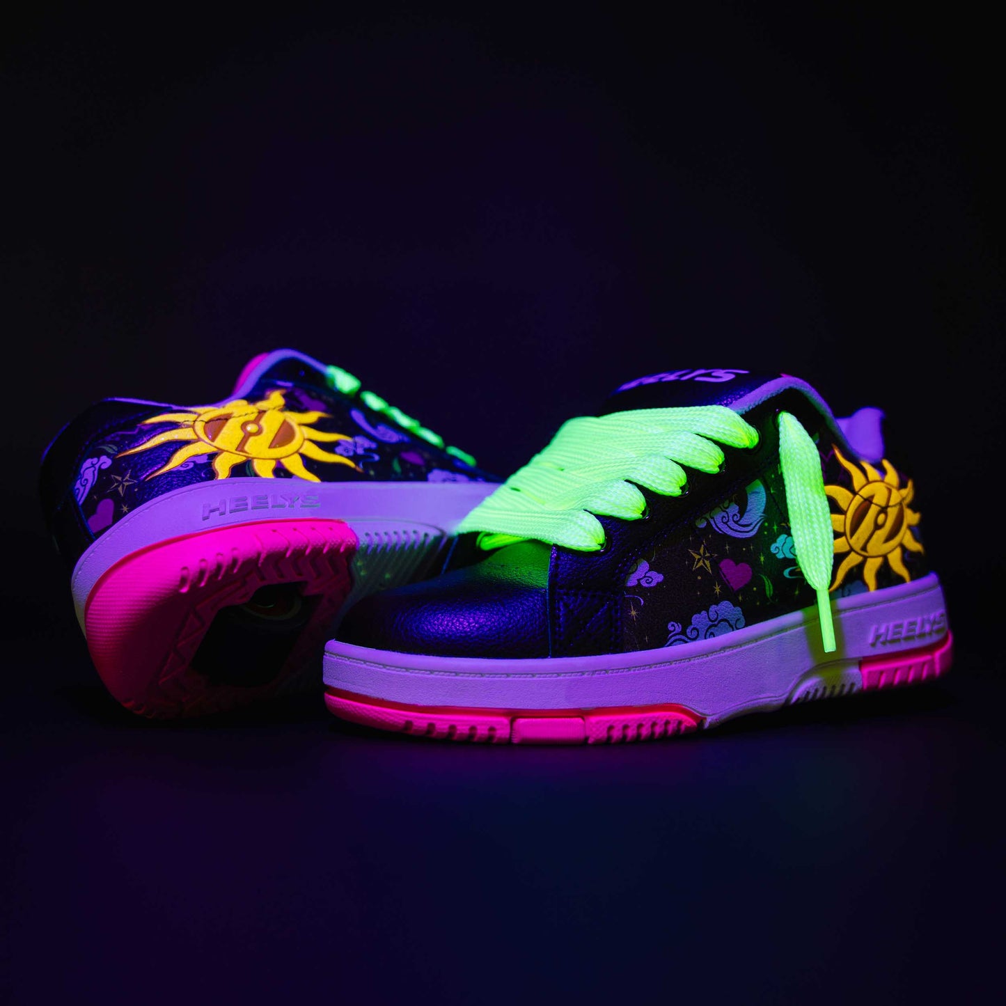 Glowing neon Heelys roller shoes with floral designs on a black background
