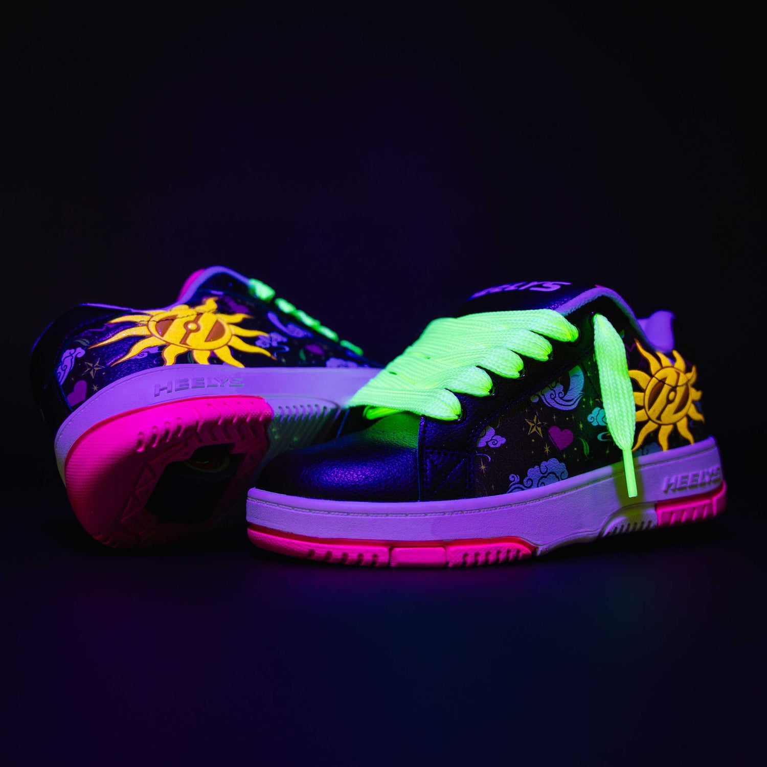 Glowing neon Heelys roller shoes with floral designs on a black background