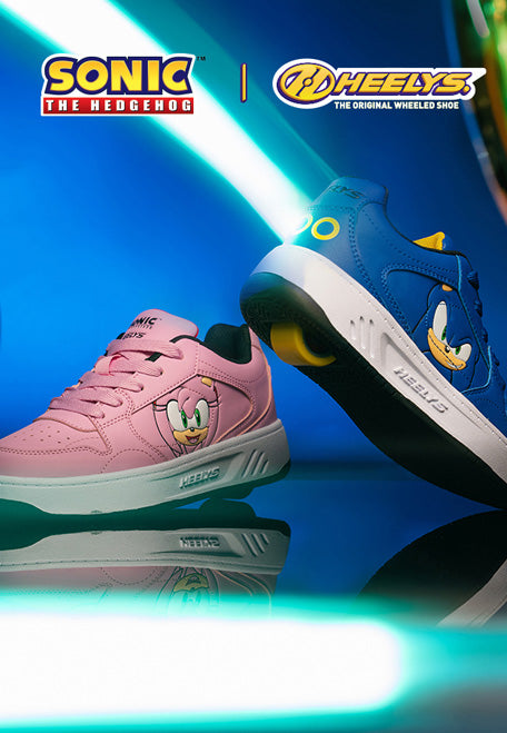 Two Sonic the Hedgehog x Heelys shoes displayed on a reflective blue surface with neon light effects. One shoe is pink with an Amy graphic, and the other is blue with a Sonic graphic.