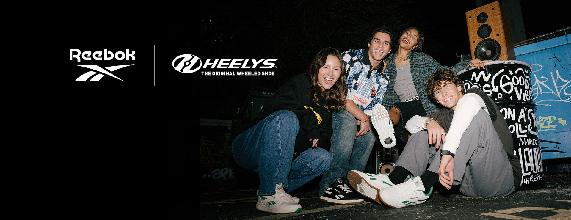 Group of people smiling, sitting on a street wearing Reebok x Heelys roller shoes.